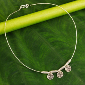 silver spirals engage the eye and mind. Sasithon Saisuk translates ancient Lanna (northern Thai) design motifs into contemporary jewelry. The pendants dangle from a silver chain, crafted by hand.